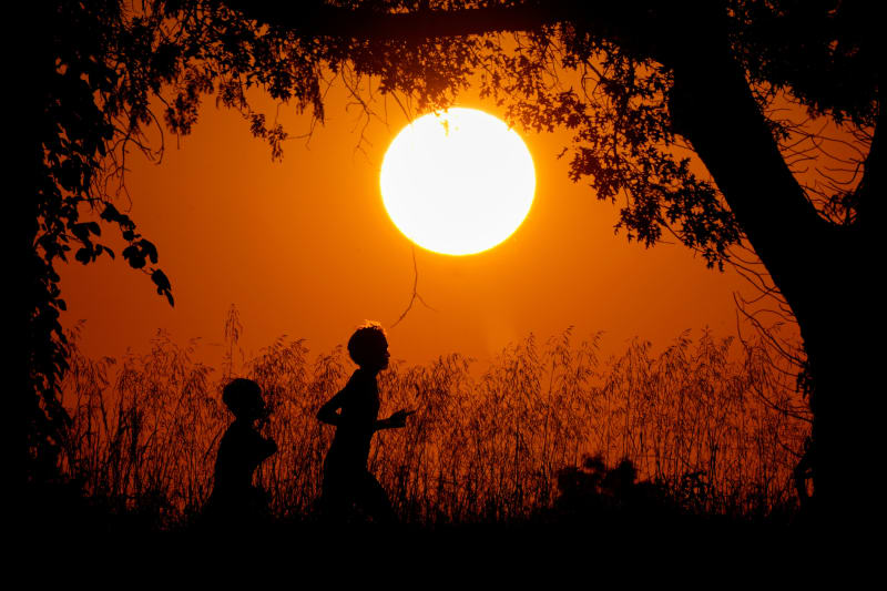People silhouetted against sunset sky while running at Shawnee Mission Park in Kansas