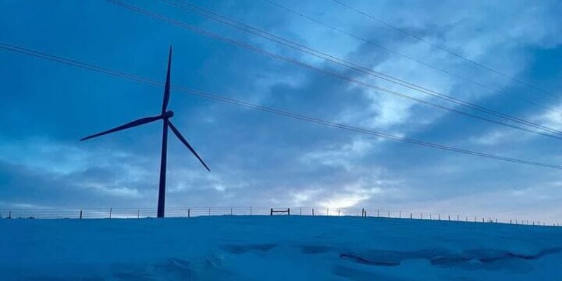 Wind turbine standing tall on farmland near Aberdeen, South Dakota against clear sky