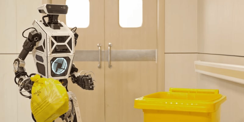 ** Humanoid robot THEMIS walking while holding a trash bag to demonstrate multitasking capabilities