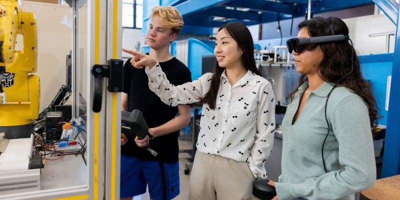 Professor Xiangyi Cheng demonstrates robotic arm to students wearing augmented reality headset