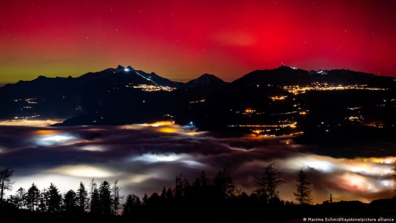 Vibrant green and purple Northern Lights glowing over snow-covered Swiss Alps at night