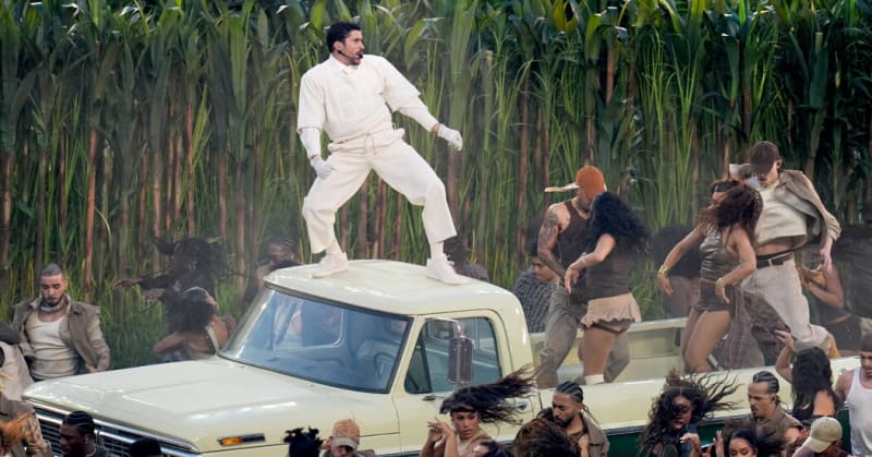 Bad Bunny performs on stage surrounded by dancers in a replica Puerto Rican sugar cane field