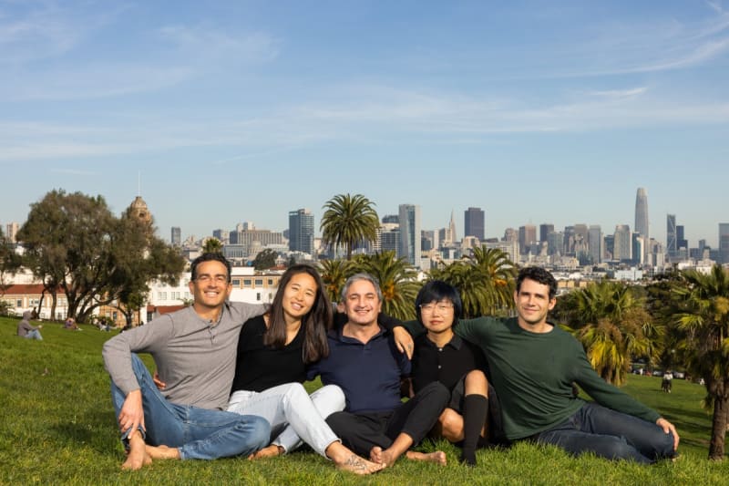Diverse team members collaborating around a table with digital AI interface displayed above them