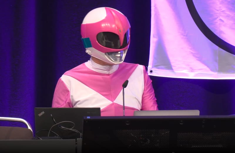 Hacktivist in Pink Power Ranger costume presenting at cybersecurity conference in Hamburg, Germany