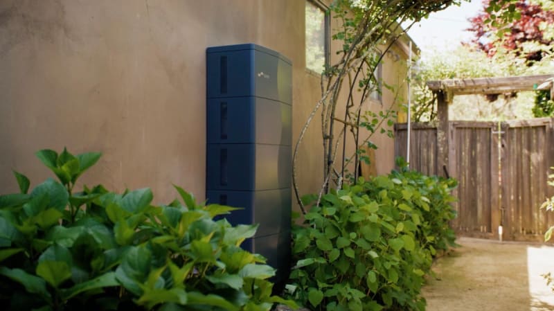 Modern home battery storage unit mounted on residential wall next to electrical panel