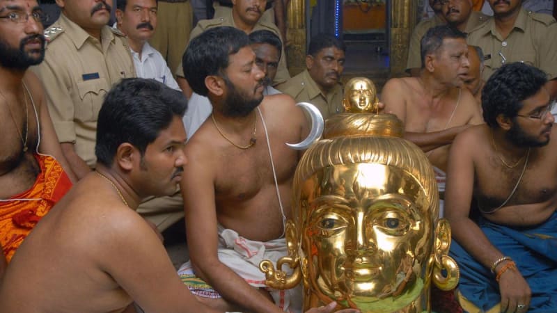 Hindu temple priest performing daily worship rituals with traditional offerings and ceremonial items