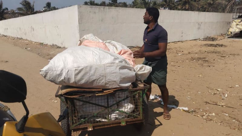 Pop-up scrap shop with tent canopy set up on Kovalam beach during circular coastal cleanup event