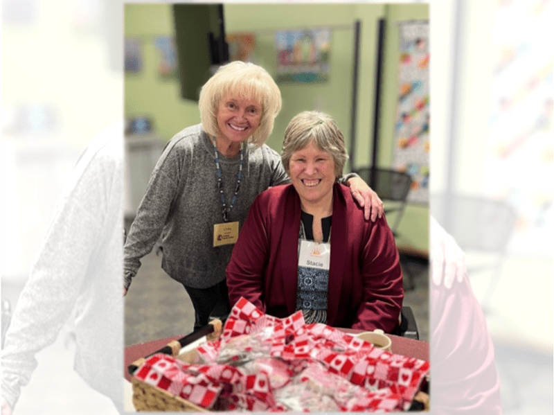 Volunteers helping senior participants with art project at table in bright community center room