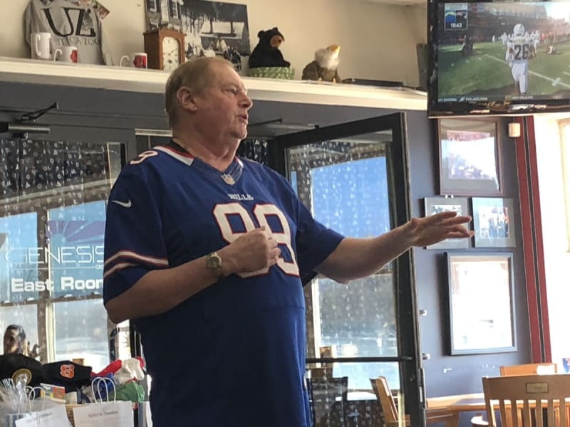People gathered at outdoor tailgate party enjoying food and watching football together for charity