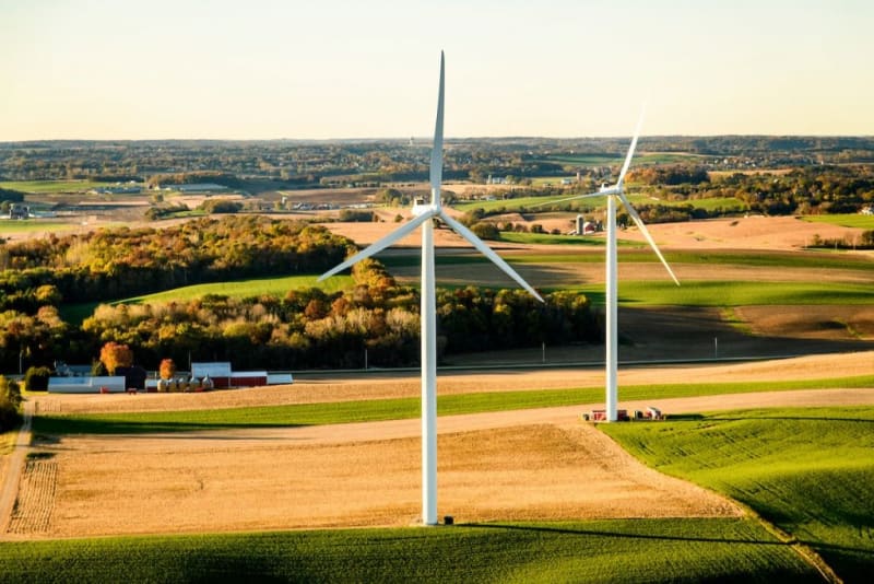 Tall white wind turbines standing in green Wisconsin farmland on a clear morning