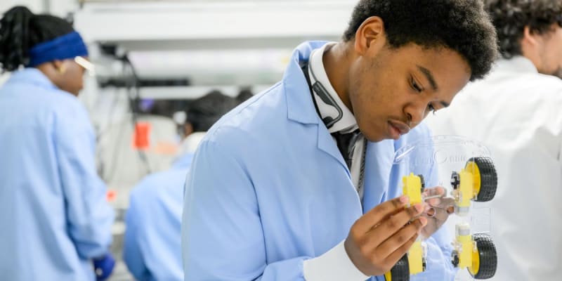College student building chemically powered model car framework in collaborative laboratory setting with engineering tools and materials