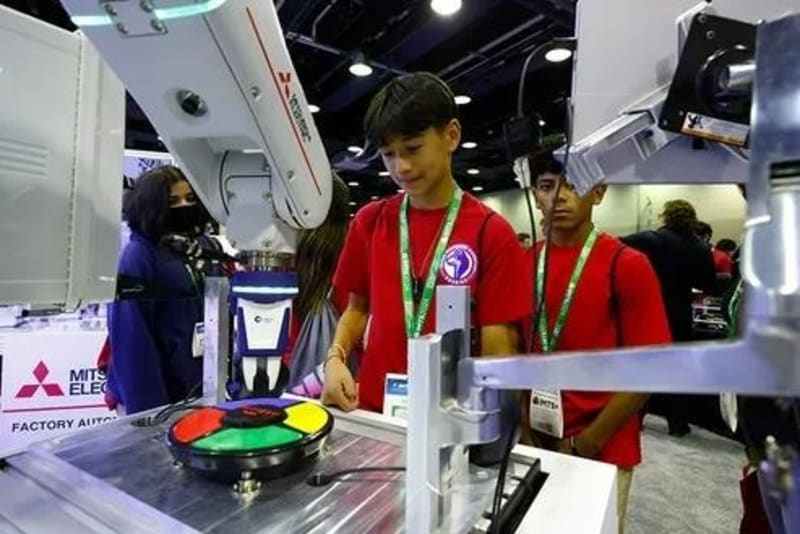 Students exploring hands-on manufacturing technology demonstrations at industrial trade show exhibition floor