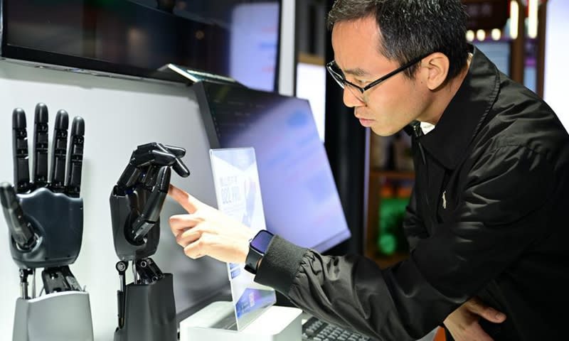 Visitor interacting with robotic intelligent hand display at China technology innovation exhibition in Shanghai