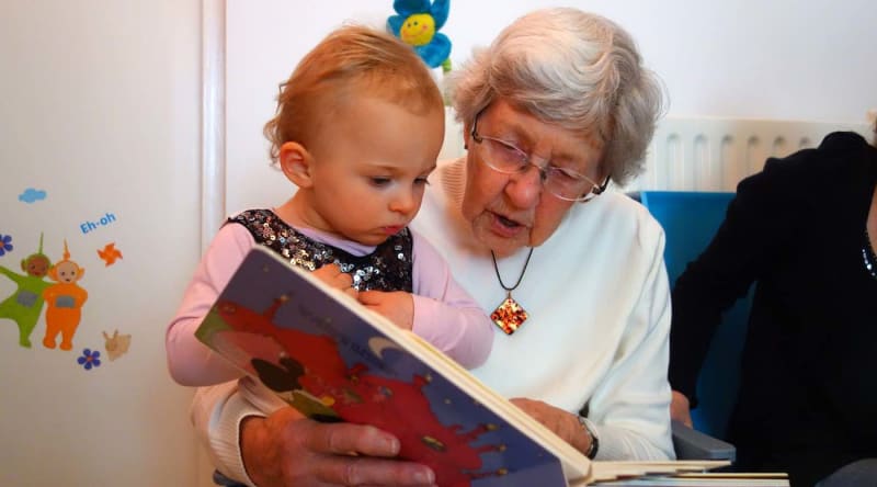 Grandmother and grandfather smiling while playing with young grandchildren at home