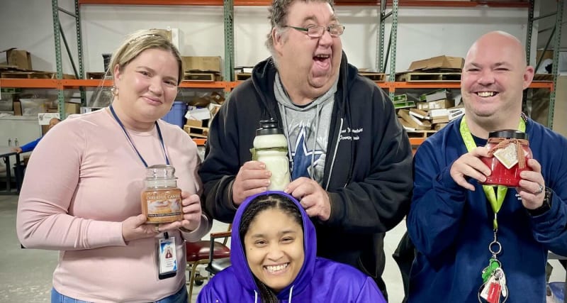 Hand-poured candles from A Cheerful Giver lined up on production table in New Jersey facility