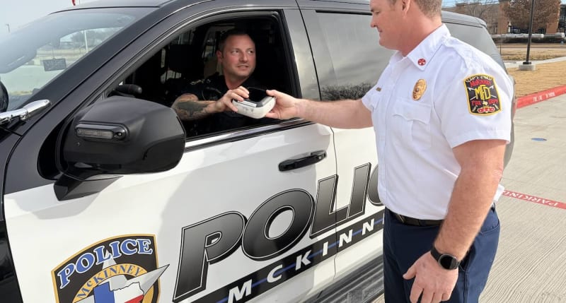 McKinney Fire and Police officials stand beside patrol car equipped with automated external defibrillator