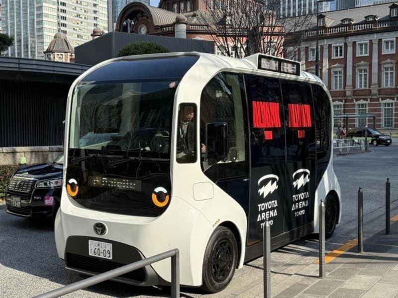 Modern autonomous bus driving on Japanese street representing future of public transportation technology