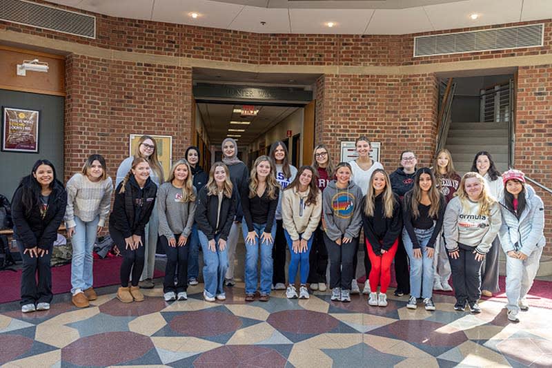Group of diverse nursing students in scrubs smiling together at Meredith College campus