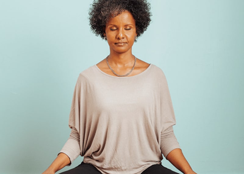 Person sitting peacefully in meditation with relaxed posture and gentle awareness