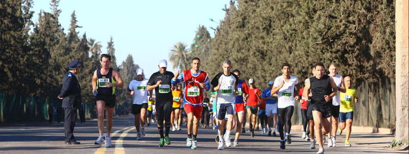 Thousands of marathon runners crowd the streets of Marrakech Morocco near historic Koutoubia Mosque
