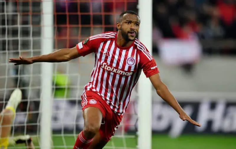 Ayoub El Kaabi celebrating in red Olympiacos jersey after scoring milestone goal in Greek league