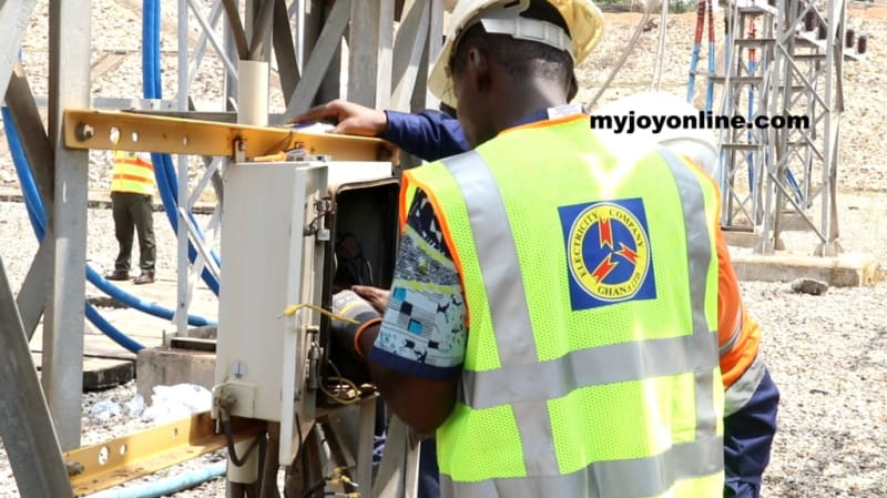 Electrical technician inspecting power distribution lines on utility pole in Ghana