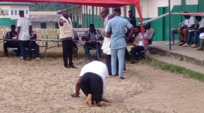 Frank Nti crawling across dusty ground toward polling station to cast his vote in Ghana