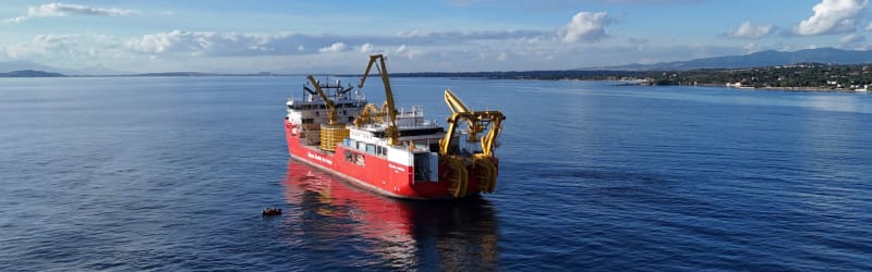 Specialized cable-laying vessel installing high-voltage underwater power cables in deep blue Mediterranean waters at record-breaking depths