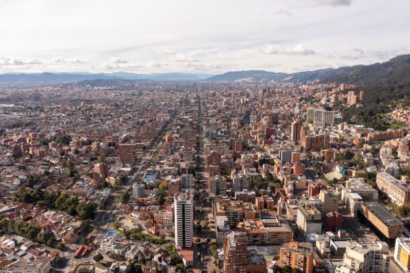Green urban park with trees and families in Bogotá neighborhood with mountains in background