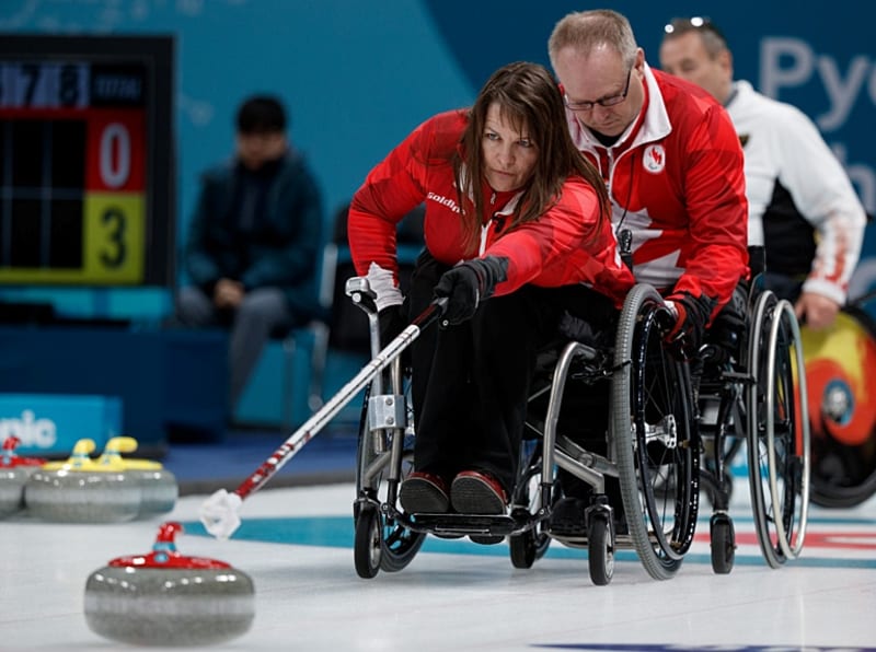 Ina Forrest in wheelchair throwing curling stone with stick at Paralympic competition