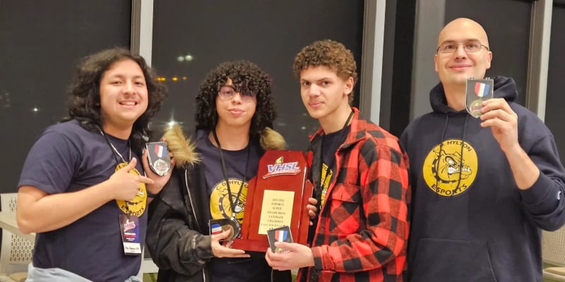 Three high school students celebrating their Virginia state esports championship win with trophy