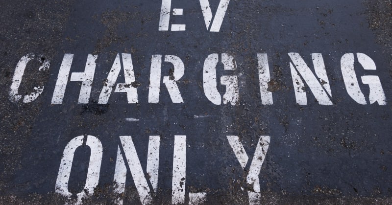 Electric vehicle charging at designated parking space in California shopping center, representing accessible clean transportation infrastructure for residents