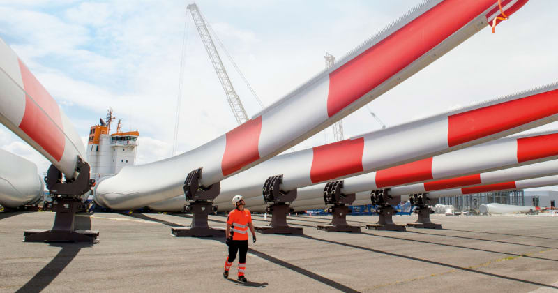 Large white wind turbine rotor blades being installed at offshore wind farm