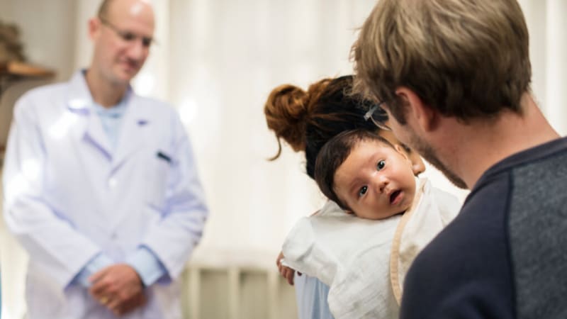 Caring pediatrician having a warm, engaged conversation with parents in a welcoming medical office setting