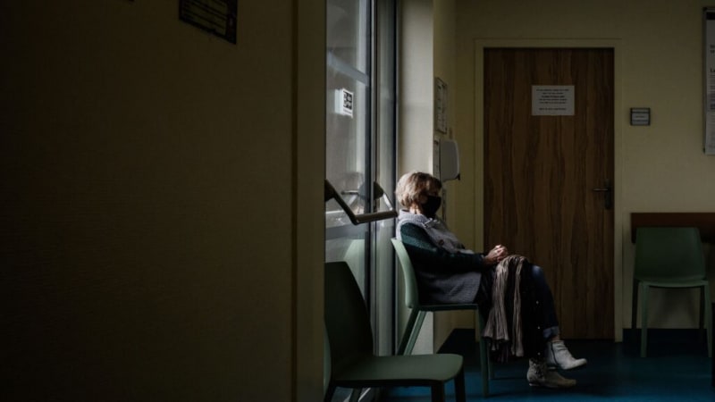 Hospital doctor speaking compassionately with patient in hospital bed surrounded by family members