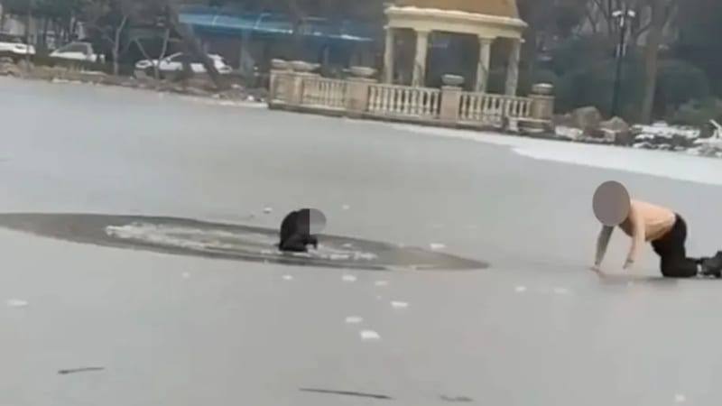 Man crawling on stomach across frozen lake ice to reach child in distress