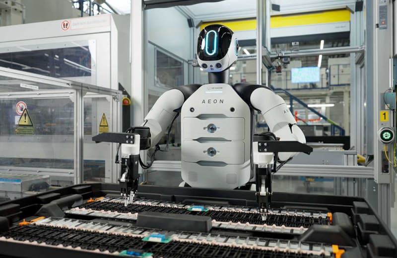 Humanoid robot with human-like upper body working alongside automotive manufacturing equipment in BMW factory