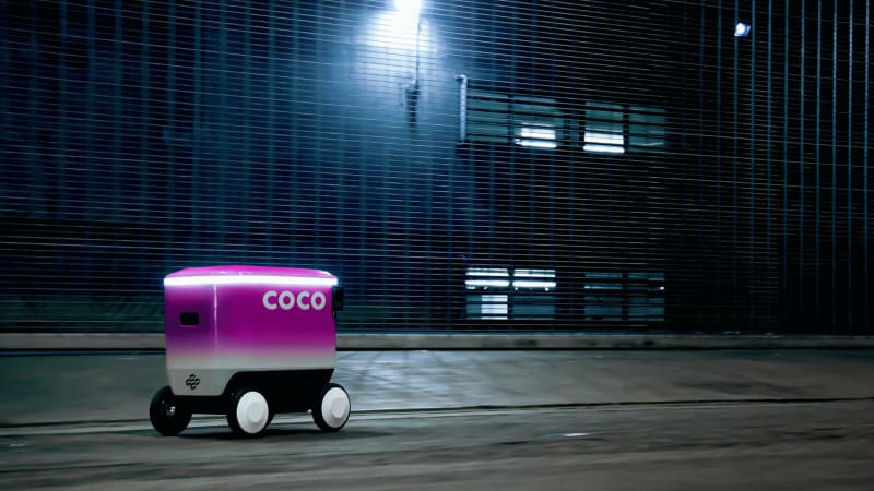 ** White and black Coco 2 autonomous delivery robot on city sidewalk ready for package delivery