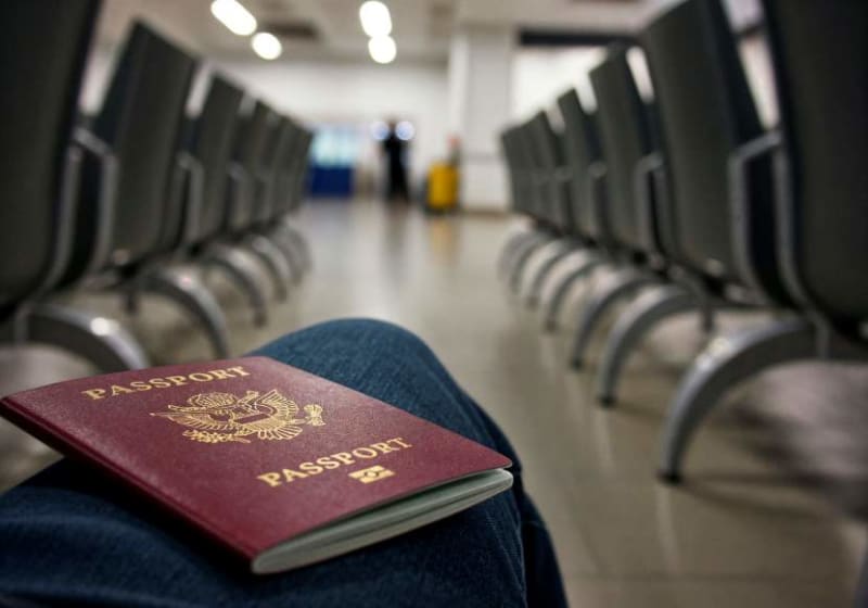 Travelers walking through modern Thai airport immigration checkpoint with welcome signs displayed