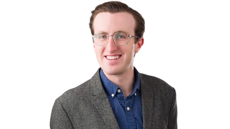 Doctoral candidate Jackson Morgan standing beside electric vehicle charging station equipment at Utah State University