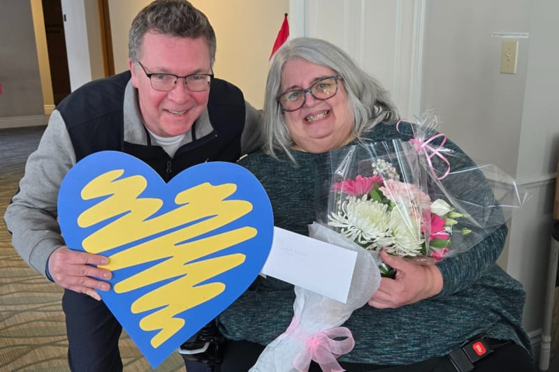 Janet Lavai holding flowers and gift cards after receiving Random Act of Kindness surprise at home