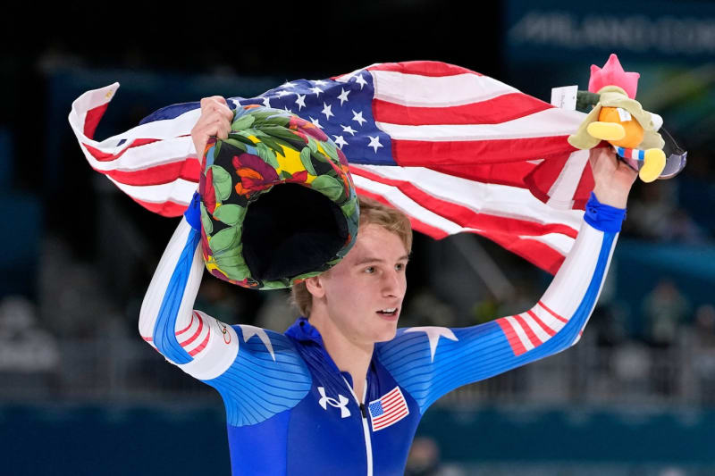 American speedskater Jordan Stolz celebrates with USA flag after winning Olympic gold medal
