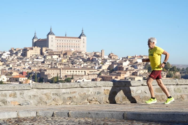 Elderly Hispanic man running on track in athletic gear showing remarkable fitness
