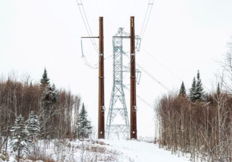 ** Electrical transmission towers carrying power lines across New England landscape under clear sky