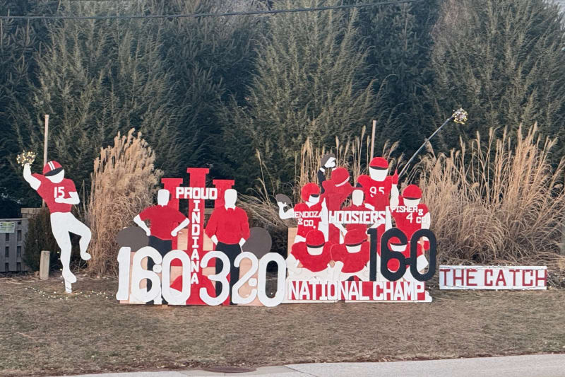 Wooden cutouts showing support for Indiana University football line a Bloomington street near Memorial Stadium