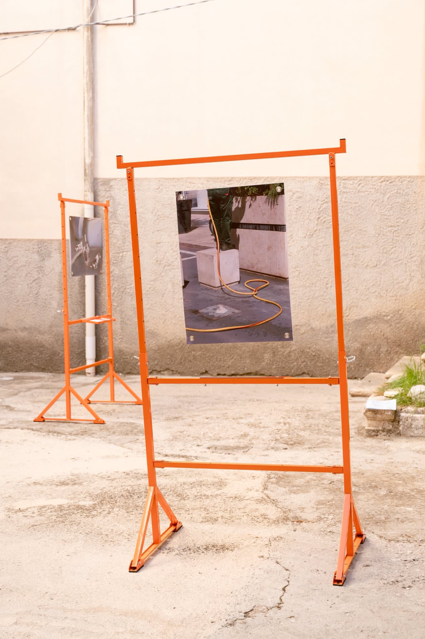 A frame holding a print of an orange hose unrolled across a forecourt