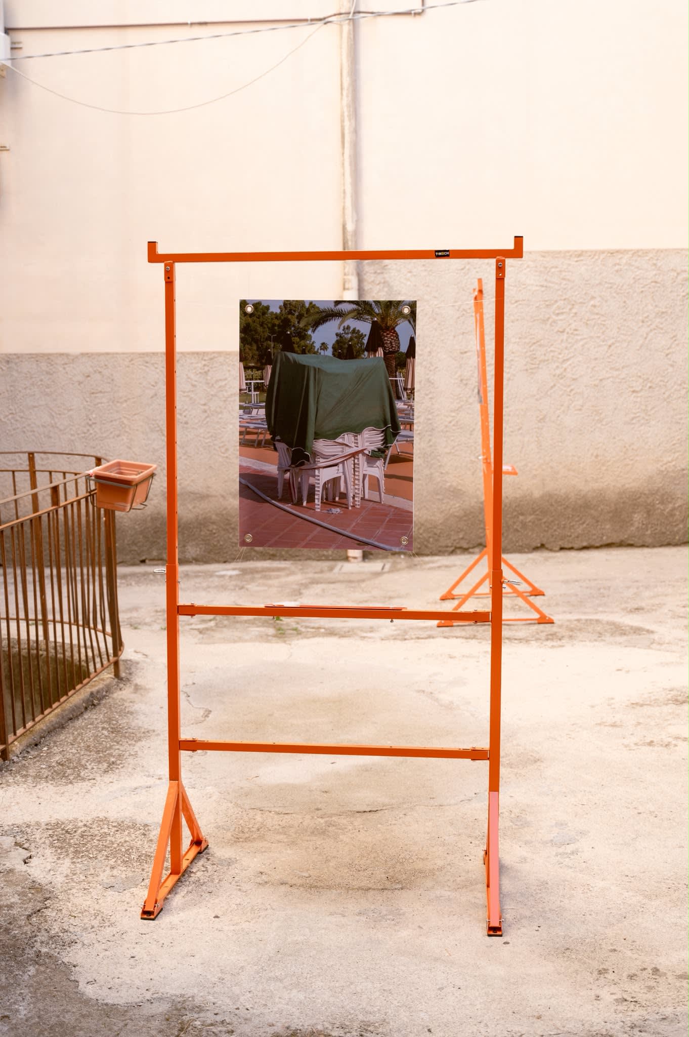 A frame holding a print of chairs stacked under a green tarpaulin