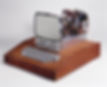 Vintage computer with exposed circuits, a small black-and-white screen, and a gray keyboard, set on a wooden base. Retro tech vibe.