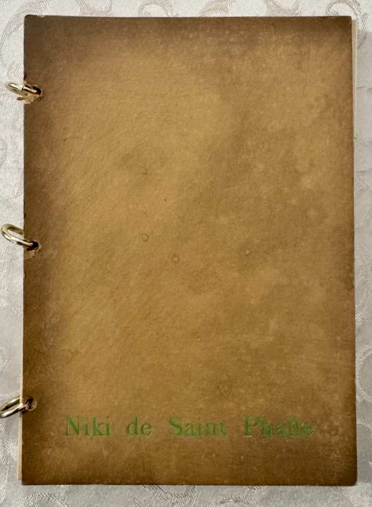 Sand-coloured suede leather artist's book cover with green stamped name and metal ring binding, featuring original ink illust