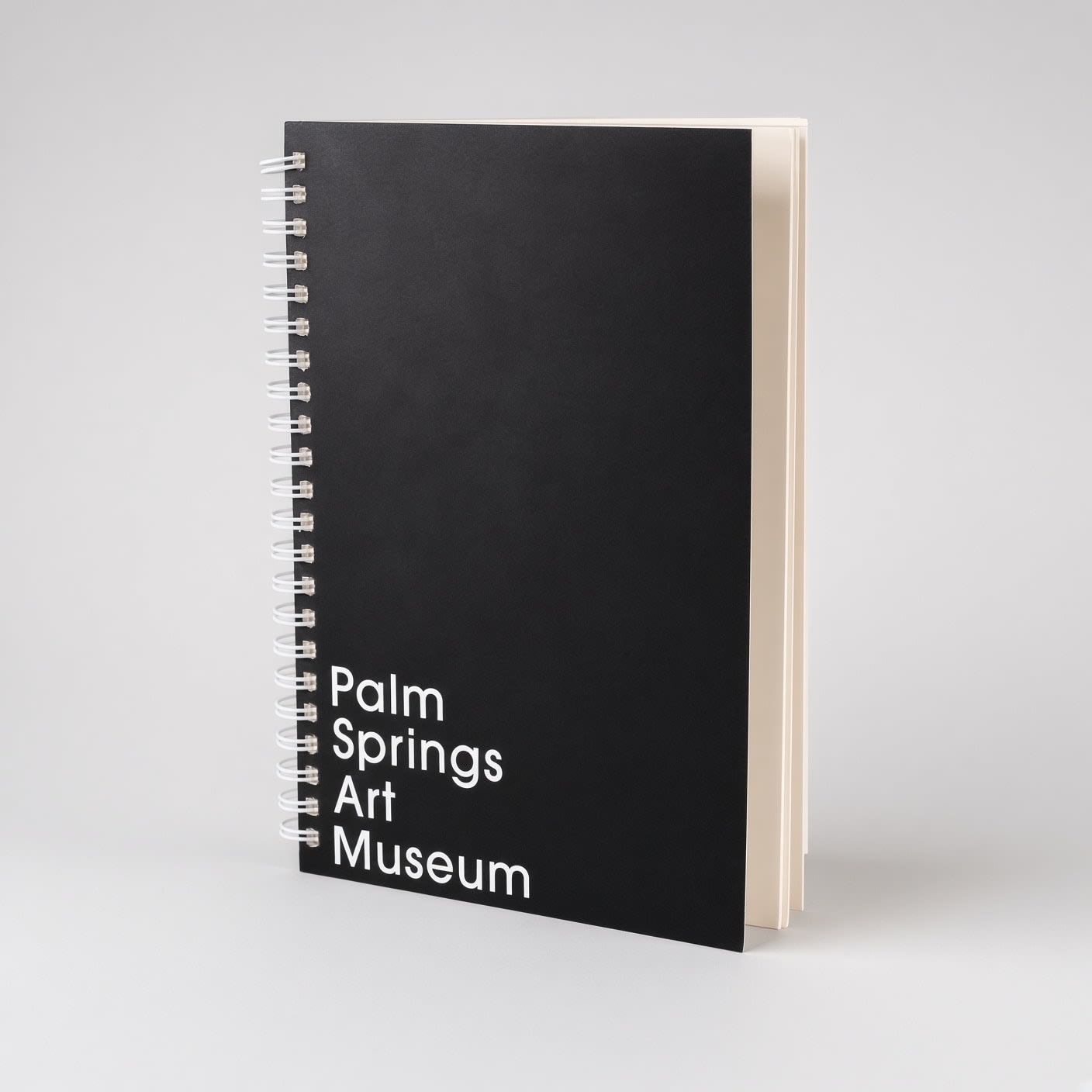 The black wire-bound notebook turned to show its coil binding and cream pages.